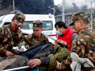 Сотрудники военизированной полиции и медицинский персонал передают пострадавшего после взрыва на заводе. Фото: AFP / Getty Images
